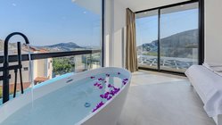 Ein modernes Badezimmer mit einer freistehenden Badewanne, gefüllt mit Wasser und lila Blütenblättern, bietet einen atemberaubenden Ausblick.